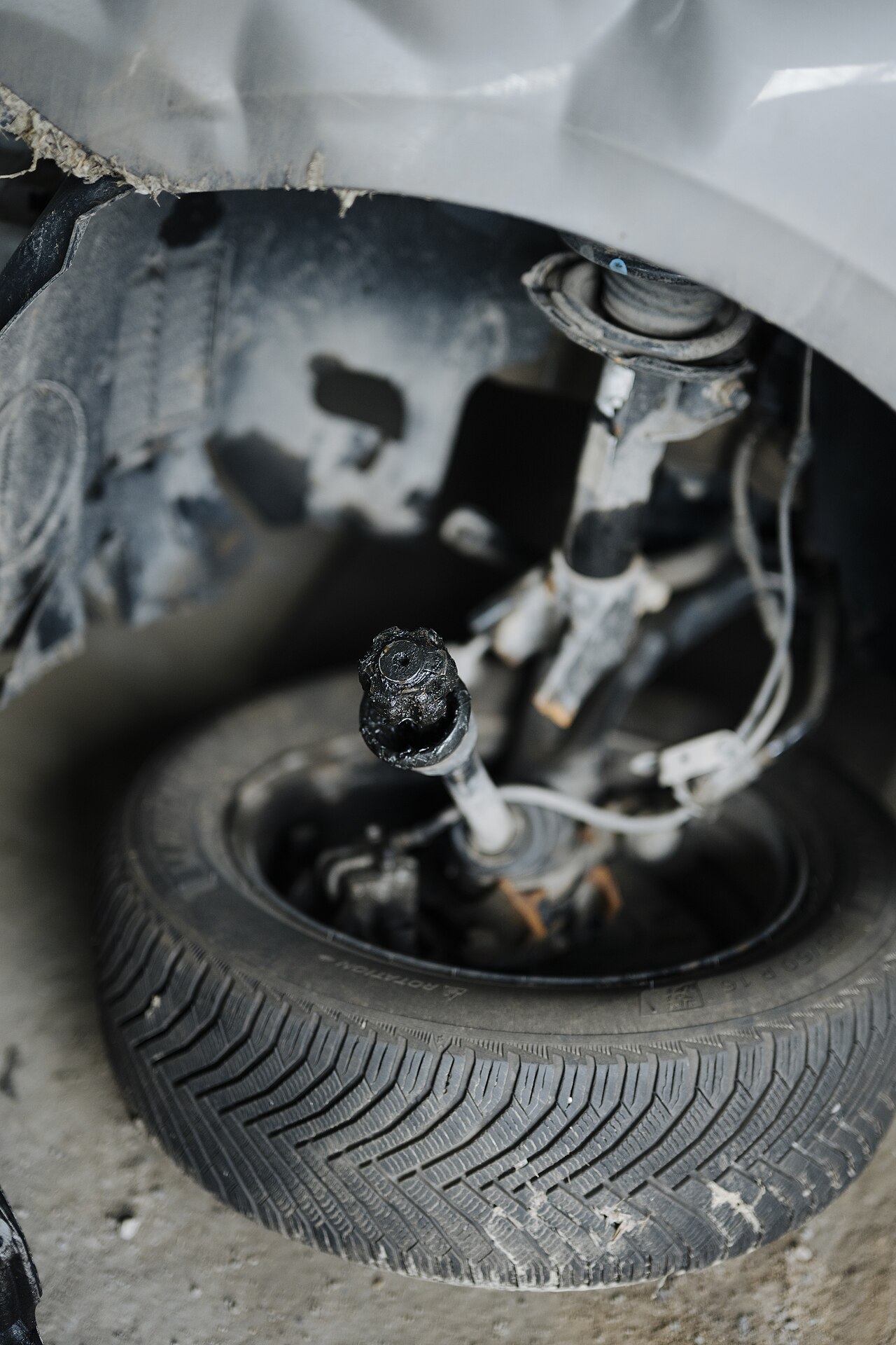 Car suspension system with wheel and tire showing damage